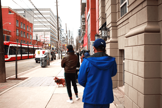 People line up, distanced from each other waiting to get into a drugstore across from StartWell on King St W in Toronto